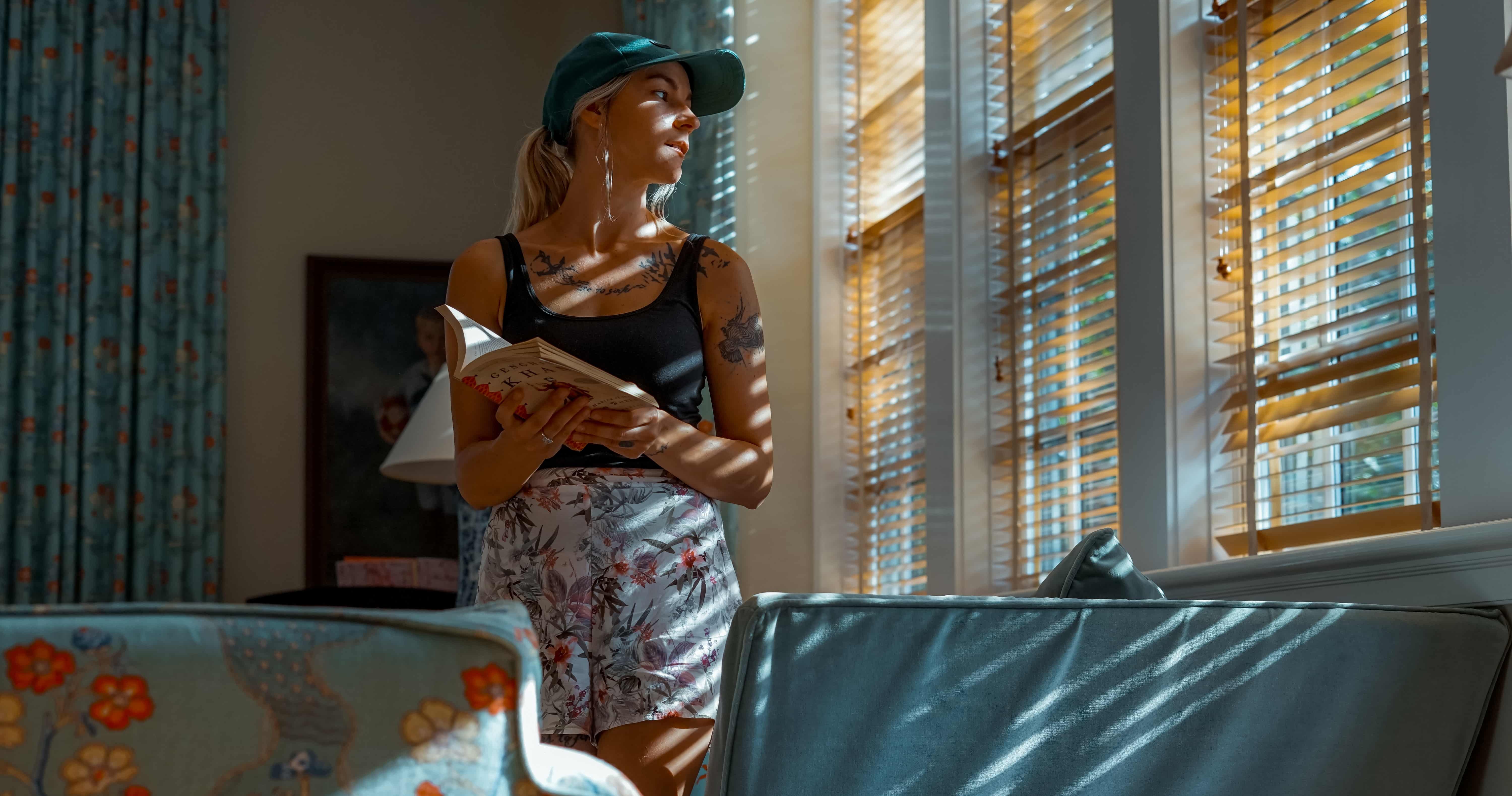 Woman with a book looking outside the window