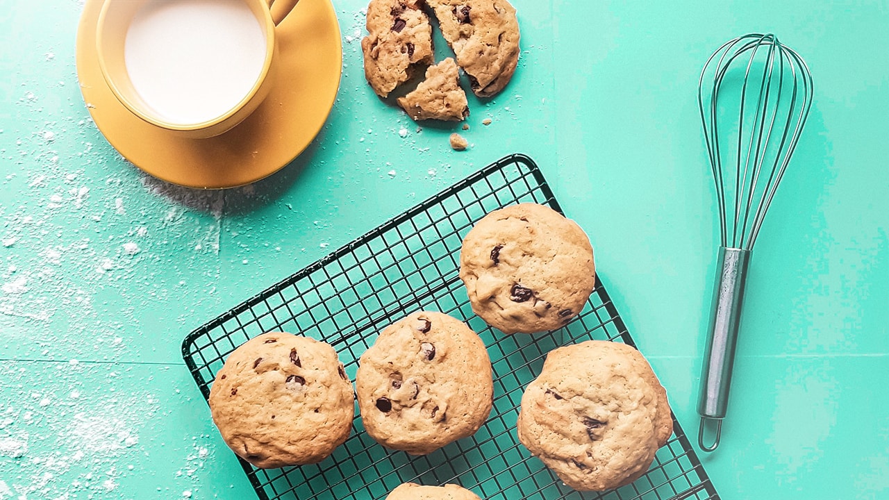 Brown cookies and a cup of milk on a green table