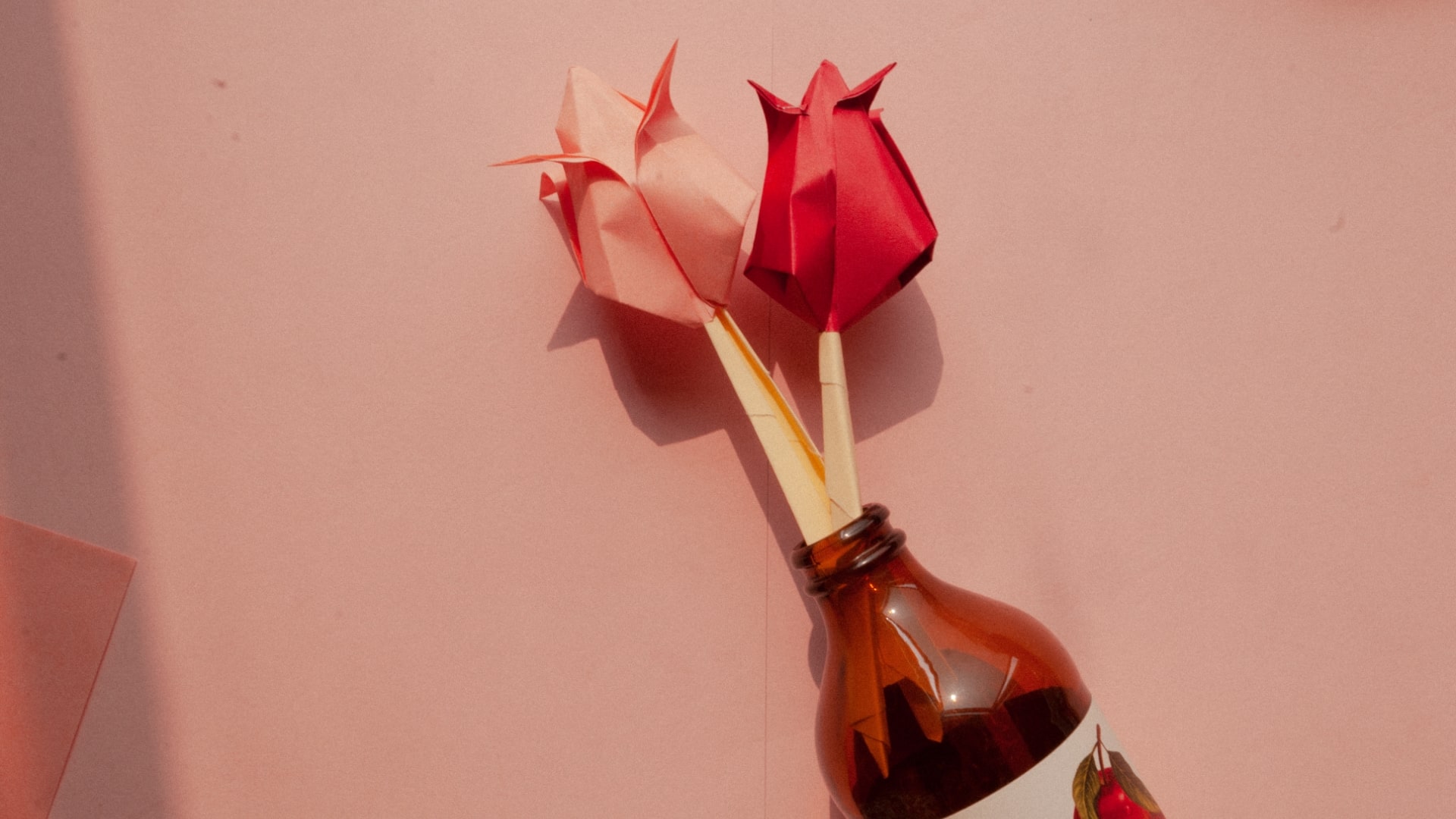 Paper crafted pink and red roses laid flat on a table