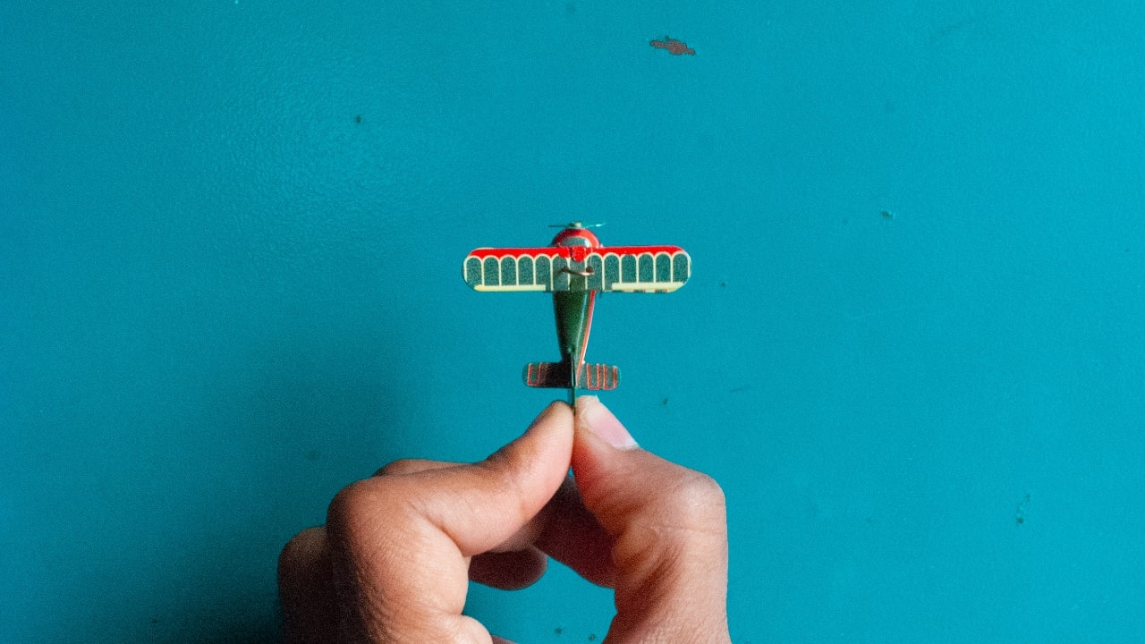 Small toy airplane in hand over a blue background