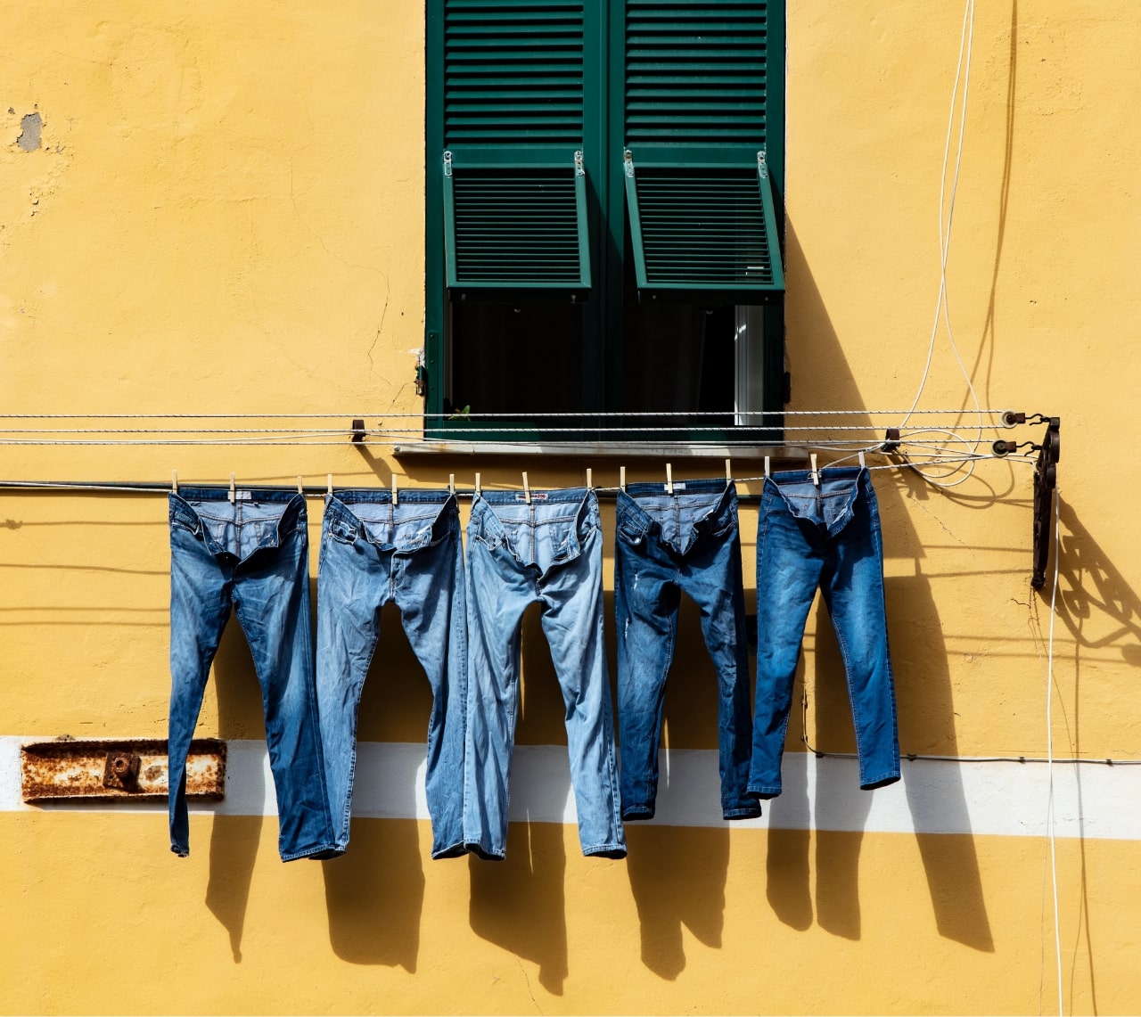 Bunch of pants hanged to dry outside a balcony in a yellow building