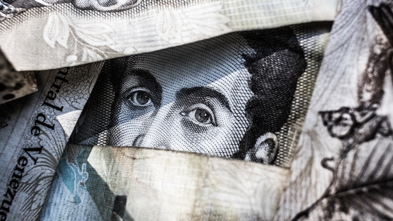 Human eyes peeking through a bunch of currency notes