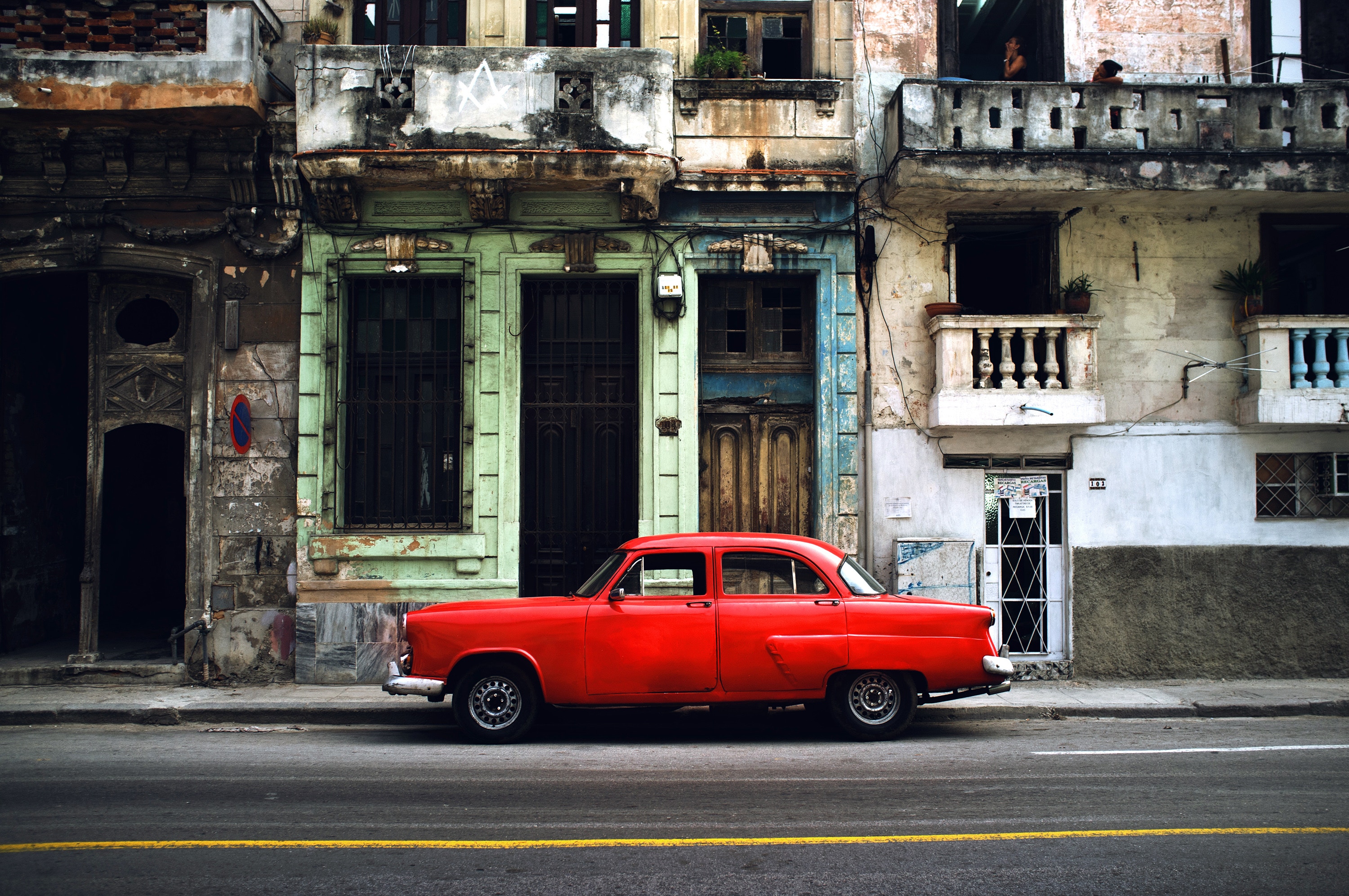 A red colored Ambassador car parked in a city area